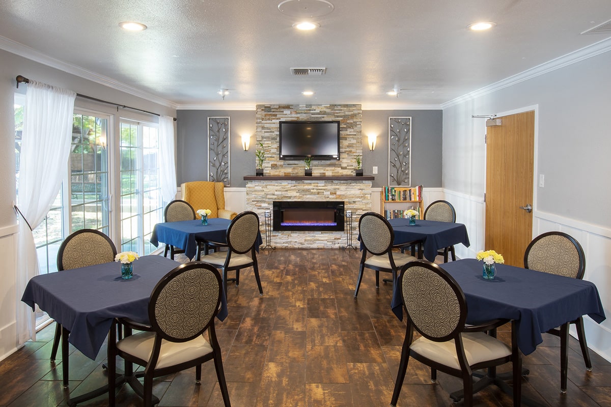Redwood Cove dining room with flat screen TV over flagstone fireplace, and tables set