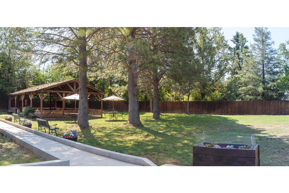 Outside of Redwood Cove with large gazebo, park benches, and tables with chairs.