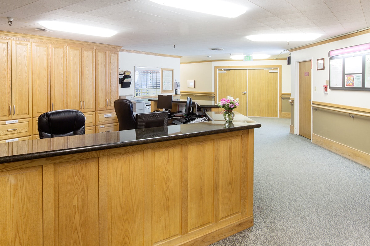 Nurses' station with computers, oak cabinets and black granite countertops.