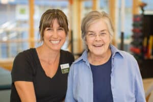 Medical professional in black shirt smiling next to female patient in blue shirt