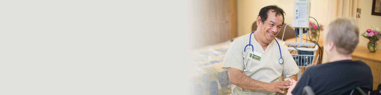 Medical professional with stethoscope around his neck holding the hand of woman in wheelchair at Redwood Cove Healthcare