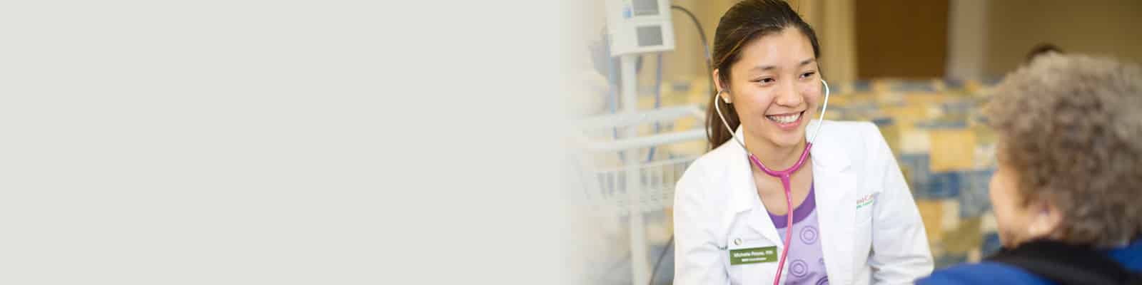 Medical professional in white lab coat smiling next to woman in blue shirt with curly hair at Redwood Cove Healthcare
